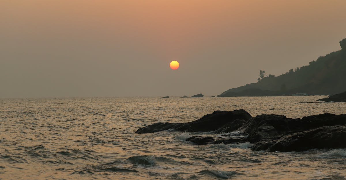 Serene sunset view at Gokarna, India with waves crashing on the rocky shore.