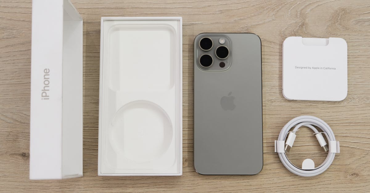 Flat lay view of the newest Apple iPhone model, box, and charging accessories on a wooden table.
