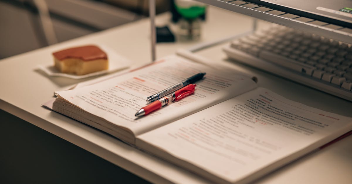 Open book with study notes, pens, and a laptop on a desk creating a focused study environment.
