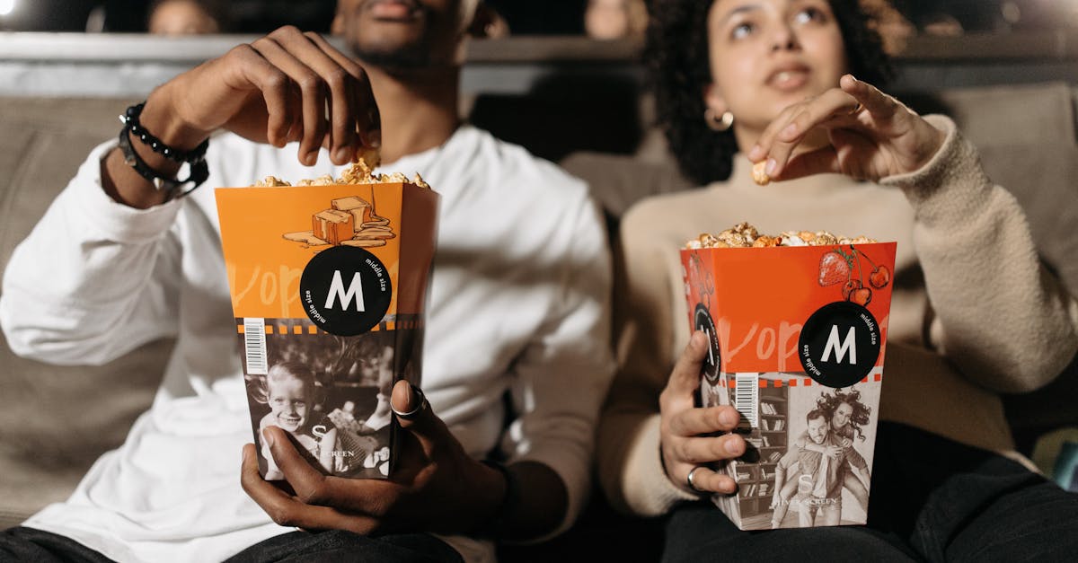 A couple enjoys popcorn while watching a movie in a theater.