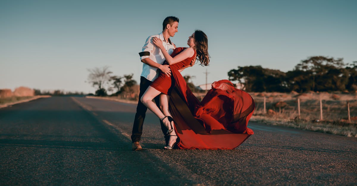 A couple in a passionate dance pose on an empty highway at sunset, showcasing love and romance.