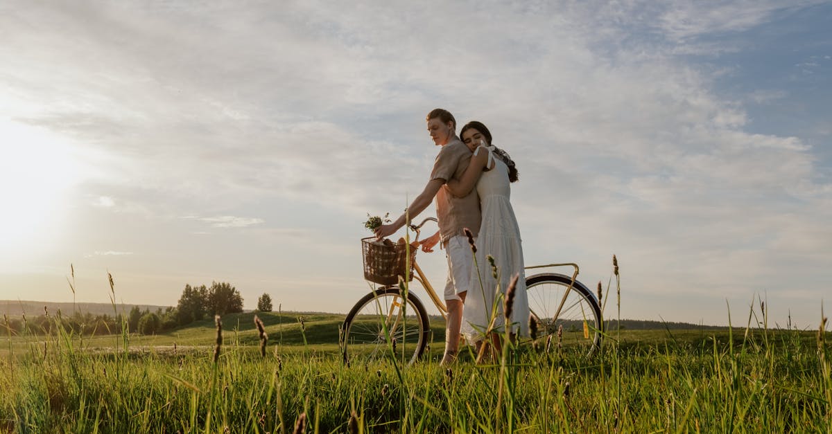 A couple embraces with a bicycle in a sunny meadow, exuding love and warmth.