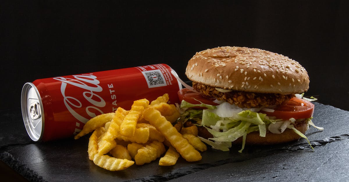 Tasty crispy chicken burger with fresh fries and a soda, perfect for a fast-food craving.