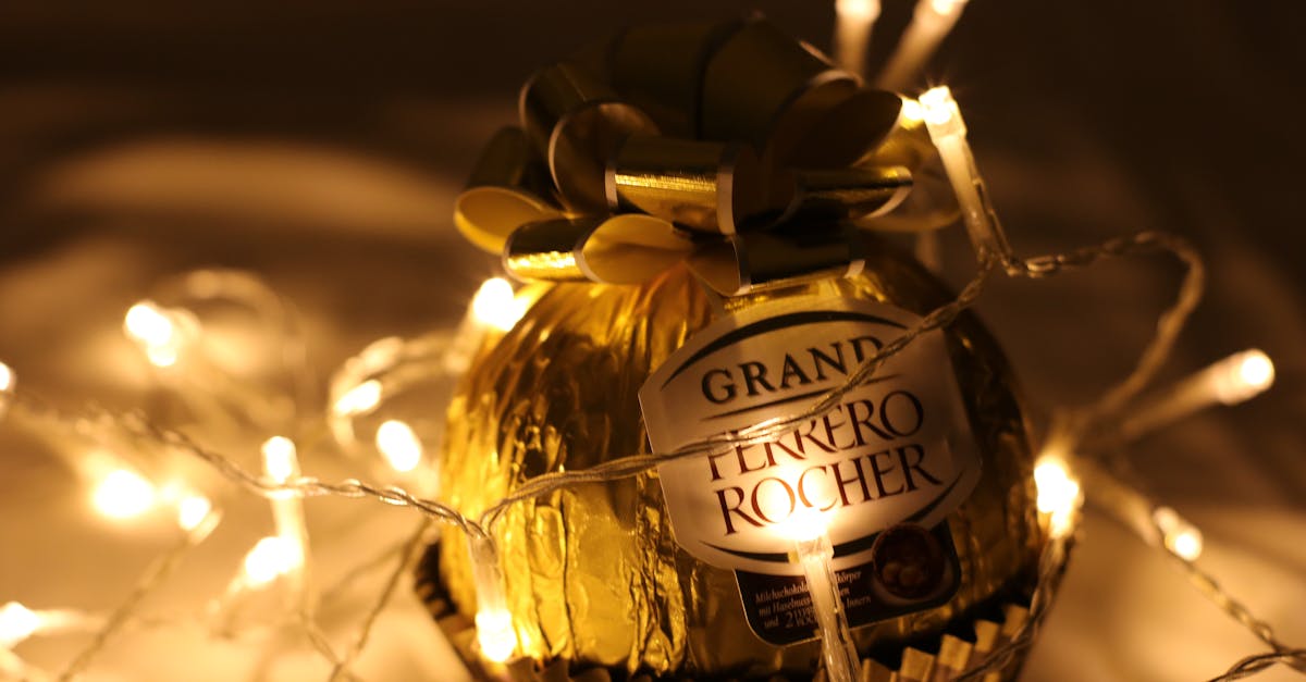 A Grand Ferrero Rocher chocolate illuminated by warm LED string lights, perfect for Christmas decor.